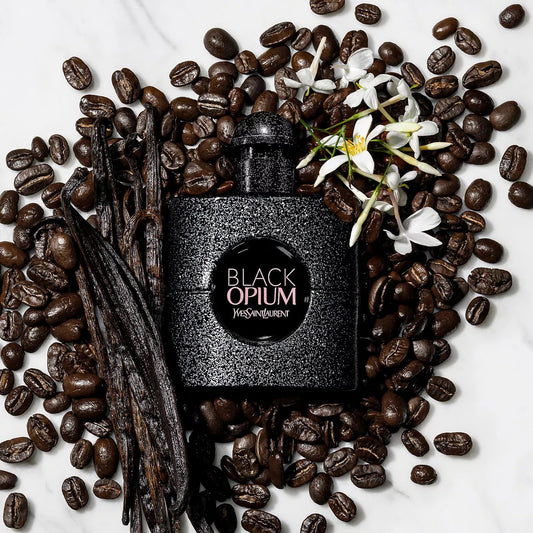 YSL Black Opium perfume surrounded by coffee beans, vanilla pods, and flowers on a white background Yves Saint Laurent Black Opium Eau de Parfum 90 ml (3 fl.oz)