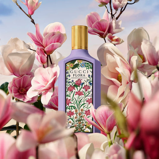Gucci Flora perfume bottle surrounded by pink flowers with a blue sky background Gucci Flora Gorgeous Magnolia Eau de Parfum 100 ml (3.4 fl.oz)