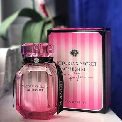 Pink Victoria's Secret Bombshell perfume bottle and packaging on a blurred background