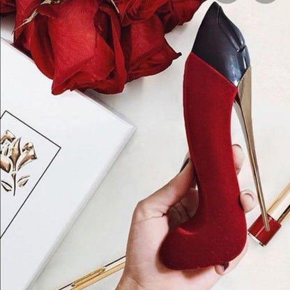 Red high-heeled shoe held by a hand with red roses and a box in the background
