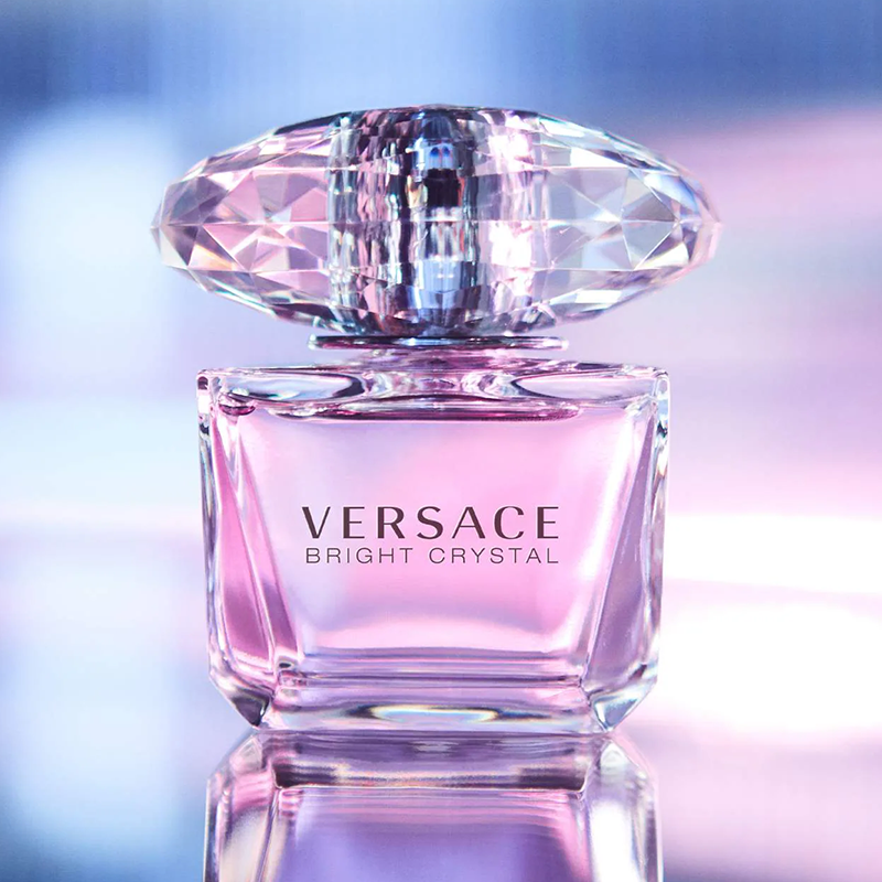 Versace Bright Crystal perfume bottle with a diamond-shaped cap on a reflective surface.