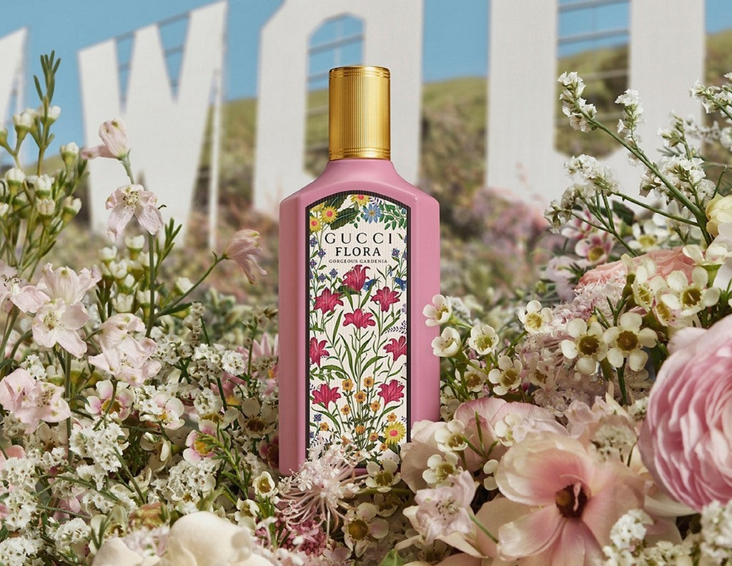 Gucci Flora perfume bottle surrounded by flowers with a scenic background