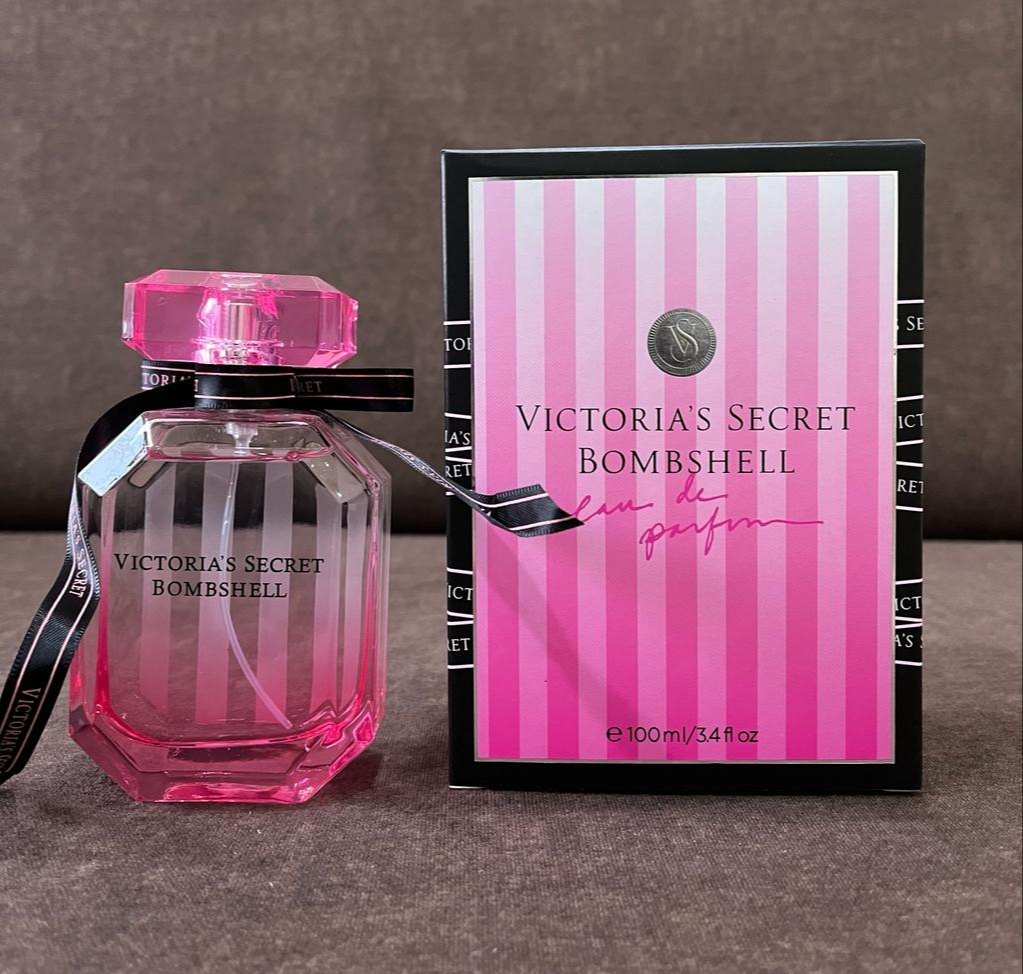 Victoria's Secret Bombshell perfume bottle and packaging on a brown surface
