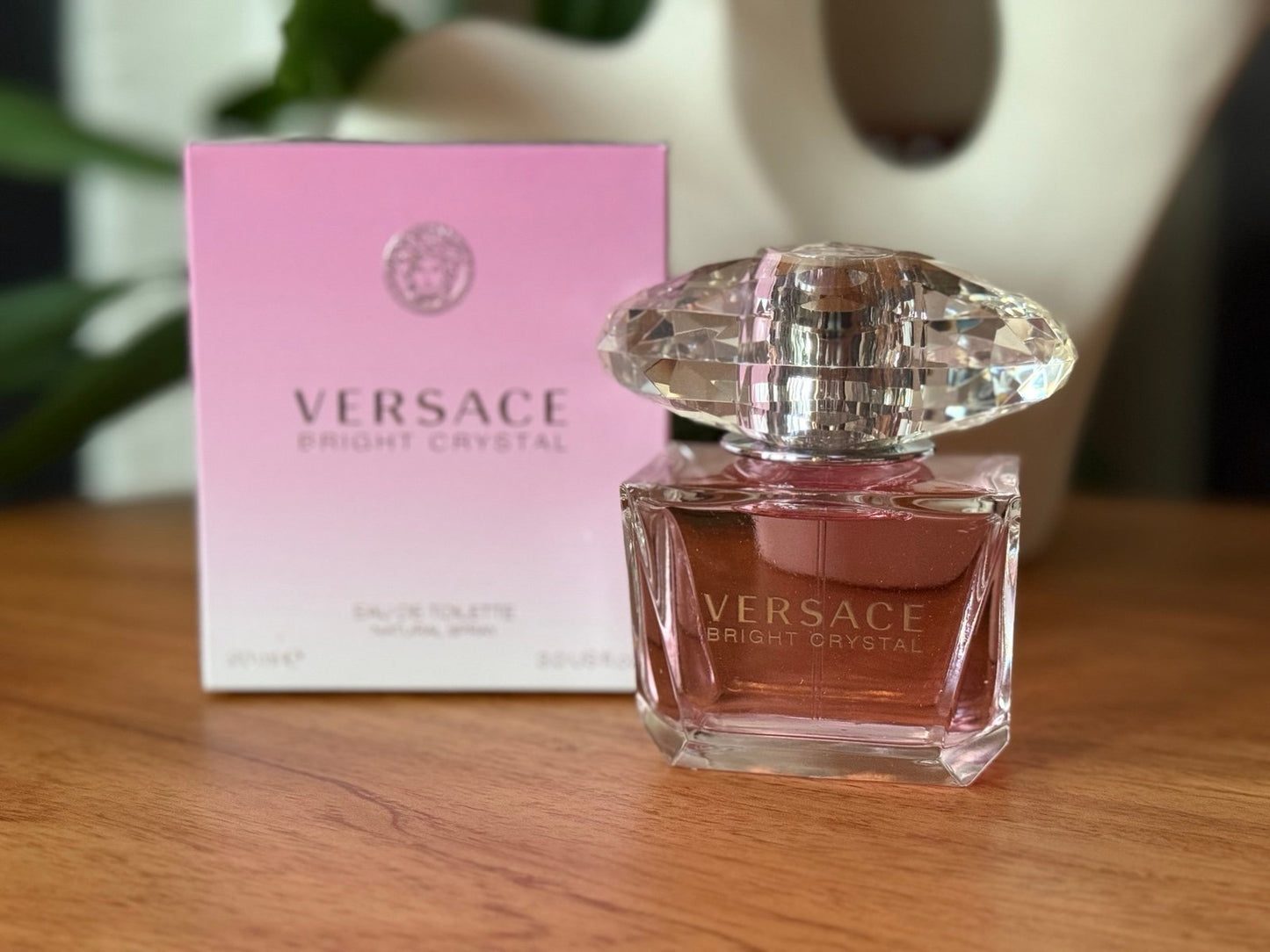 Versace Bright Crystal perfume bottle and packaging on a wooden surface