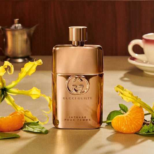 Rose gold Gucci perfume bottle on a table with oranges and flowers Gucci Guilty Eau de Parfum Intense Pour Femme 90 ml (3 fl.oz)
