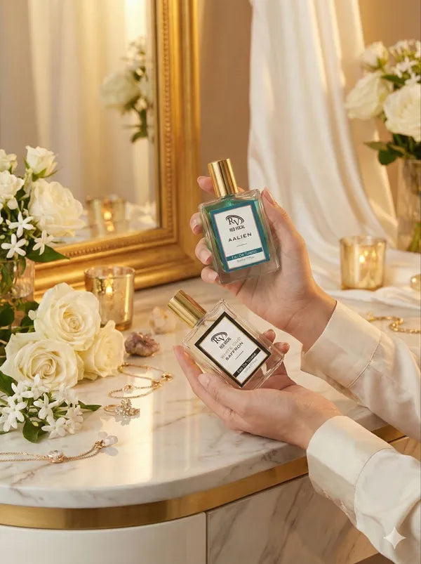 Person holding two perfume bottles on a decorative table with flowers and candles in the background Red Vocal Aalien & White Oud Saffron Premium Perfume Set | Unisex Eau De Toilette | 2 x 50ml 