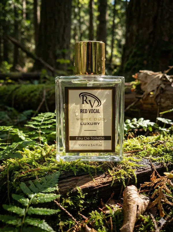 Perfume bottle labeled 'Red Vocal' on a forest floor with trees and foliage in the background Red Vocal White Oud Luxury Premium Perfume Eau De Toilette – Unisex 100ml Bold & Long-Lasting Fragrance