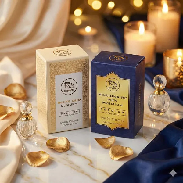 Two perfume boxes, one gold and one blue, on a marble surface with decorative elements.