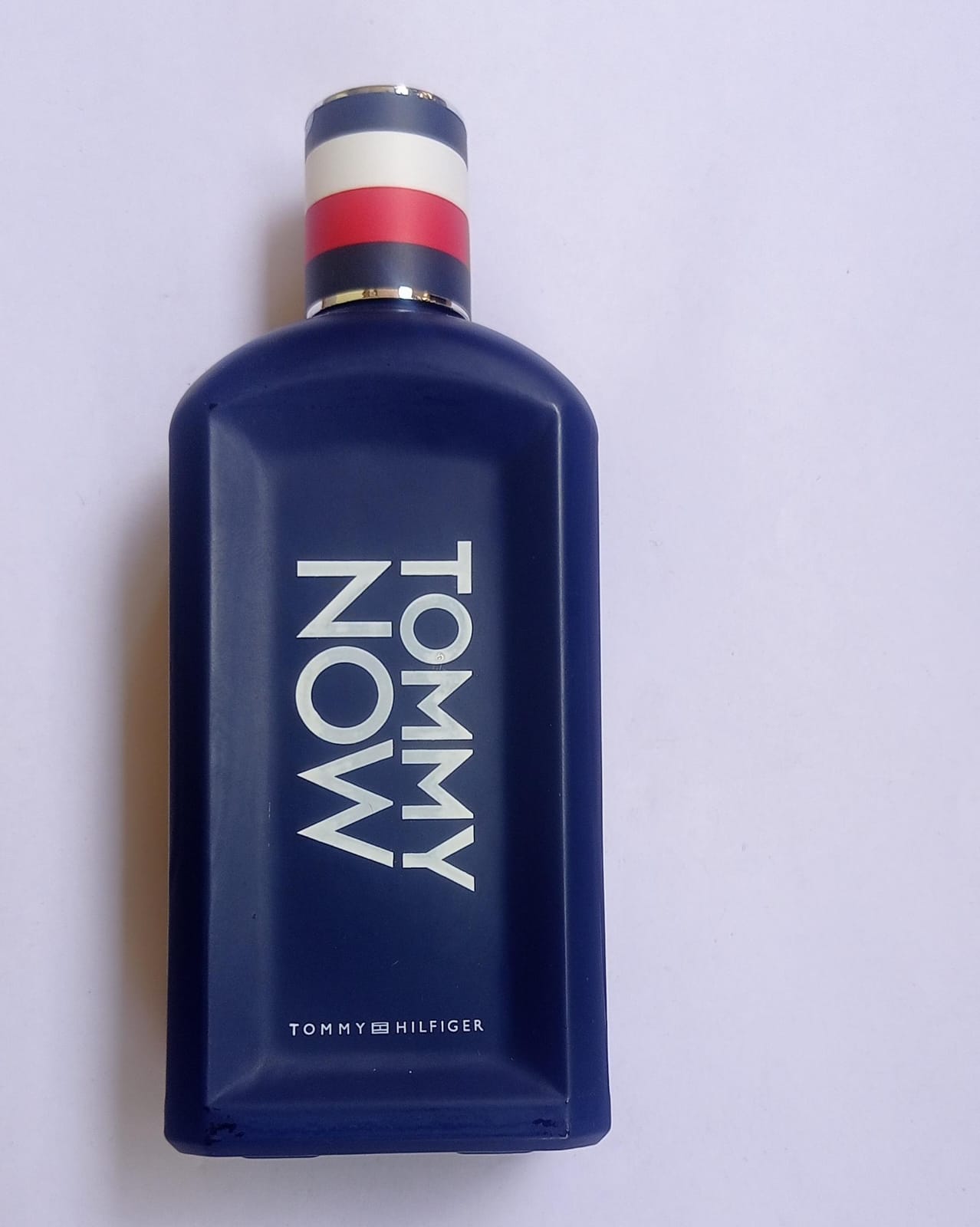 A blue bottle of Tommy Hilfiger Tommy Now Eau de Toilette with a white and red cap, labeled with the brand and product name.