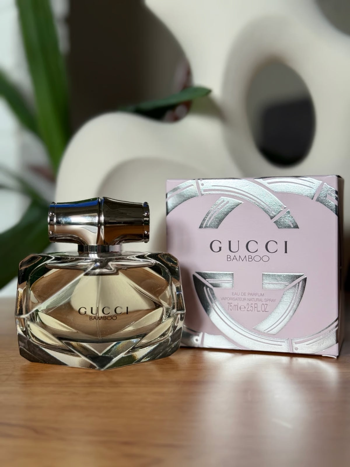 Gucci Bamboo perfume bottle and packaging on a wooden surface with a blurred background Gucci Bamboo Eau de Parfum 75 ml (2.5 fl.oz)